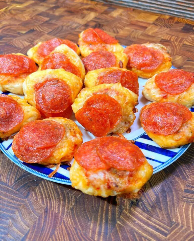 A plate of delectable Pizza Bites with melted cheese and crispy crusts, arranged in a circular pattern on a blue and white striped plate placed on a wooden surface.