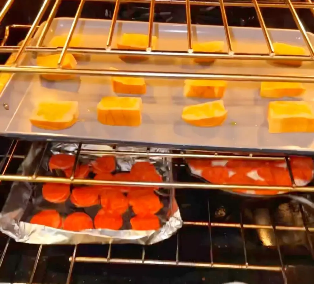 view of an oven with a sheet pan toasting hawaiian bread crostini, pepperoni pizza dip, and extra pepperoni to add on top.
