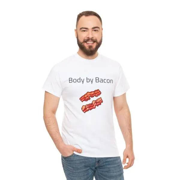 A smiling man with a beard is wearing the "Body by Bacon" T-shirt, which displays the phrase along with an image of delicious bacon strips. He stands casually, with one hand in his pocket and the other at his side.