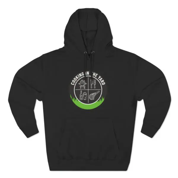 The Cooking In The Yard Hoodie is a black sweatshirt adorned with a circular logo showcasing white line art of cooking utensils, a fish, and a bottle. Surrounding the circle is the text "Cooking in the Yard," and at the bottom, there's a green shaded section that adds an appetizing element to this creative design.