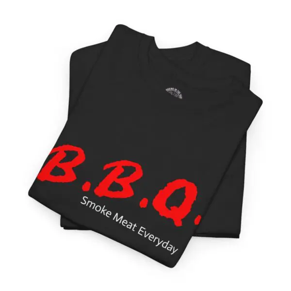 The BBQ Dare TShirt features a stack of black T-shirts adorned with bold red "B.B.Q." letters on the front. Beneath, in smaller white text, it declares "Smoke Meat Everyday," making it a perfect choice for any grill enthusiast.