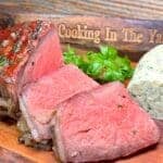 sliced beef tomahawk steak next to whiskey infused compound butter with garlic and shallots.