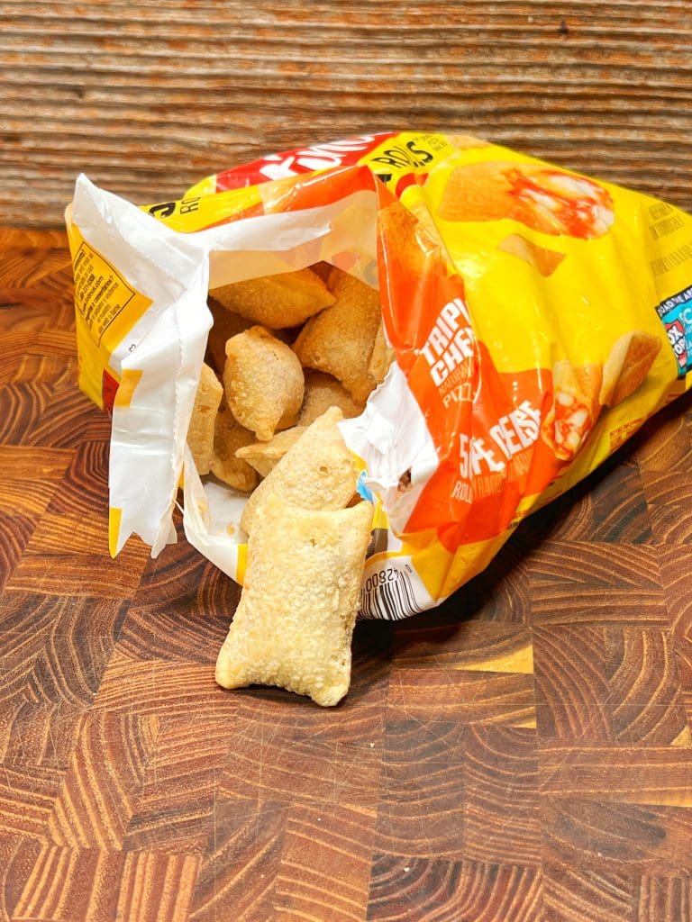 An open bag of shrimp chips sits on a wooden table, a few light, crispy chips spilling out. The yellow packaging, adorned with shrimp imagery, hints at the perfect snack recipe for those who crave something unique and delicious.