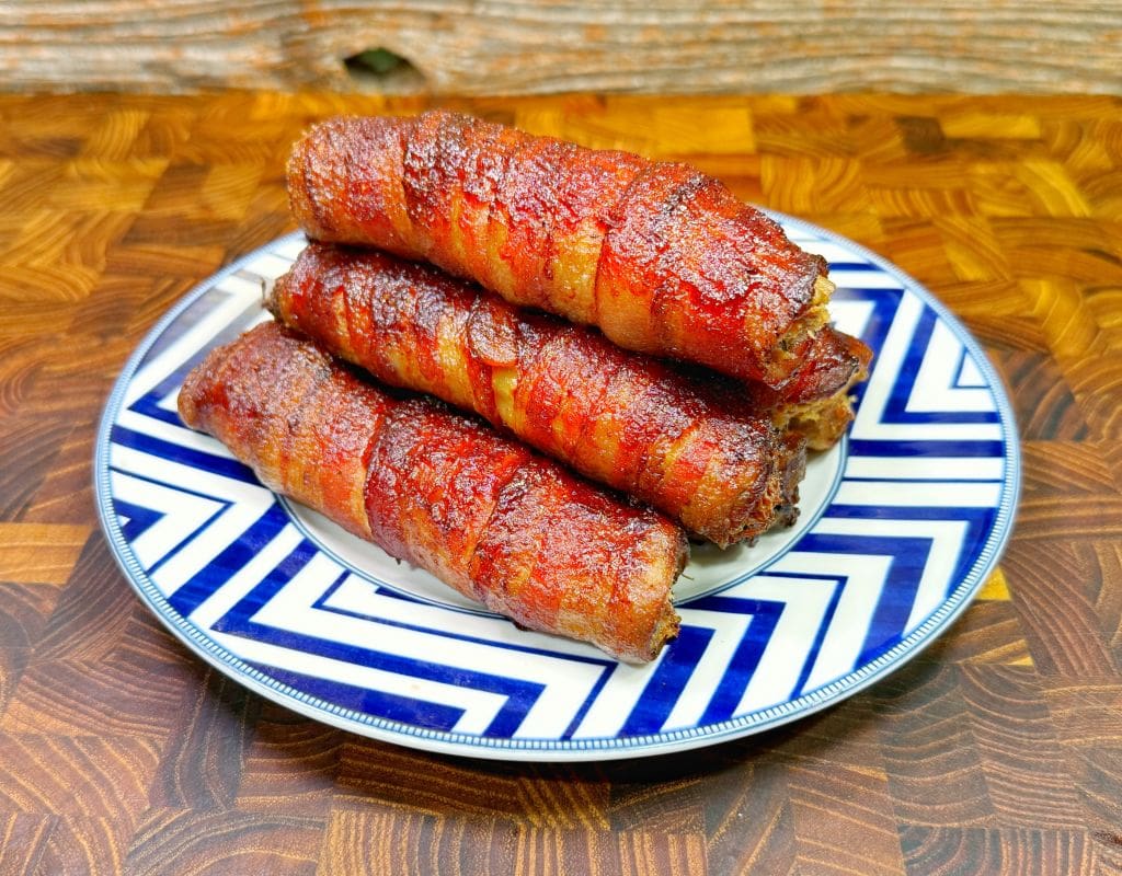a plate with a stack of bacon wrapped texas twinkies with manicotti pasta shells, cream cheese, brisket, cheese, and jalapenos.