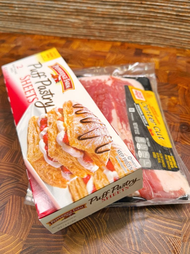 A box of Pepperidge Farm Puff Pastry Sheets rests on top of a package of beef center cut steak on a wooden surface.