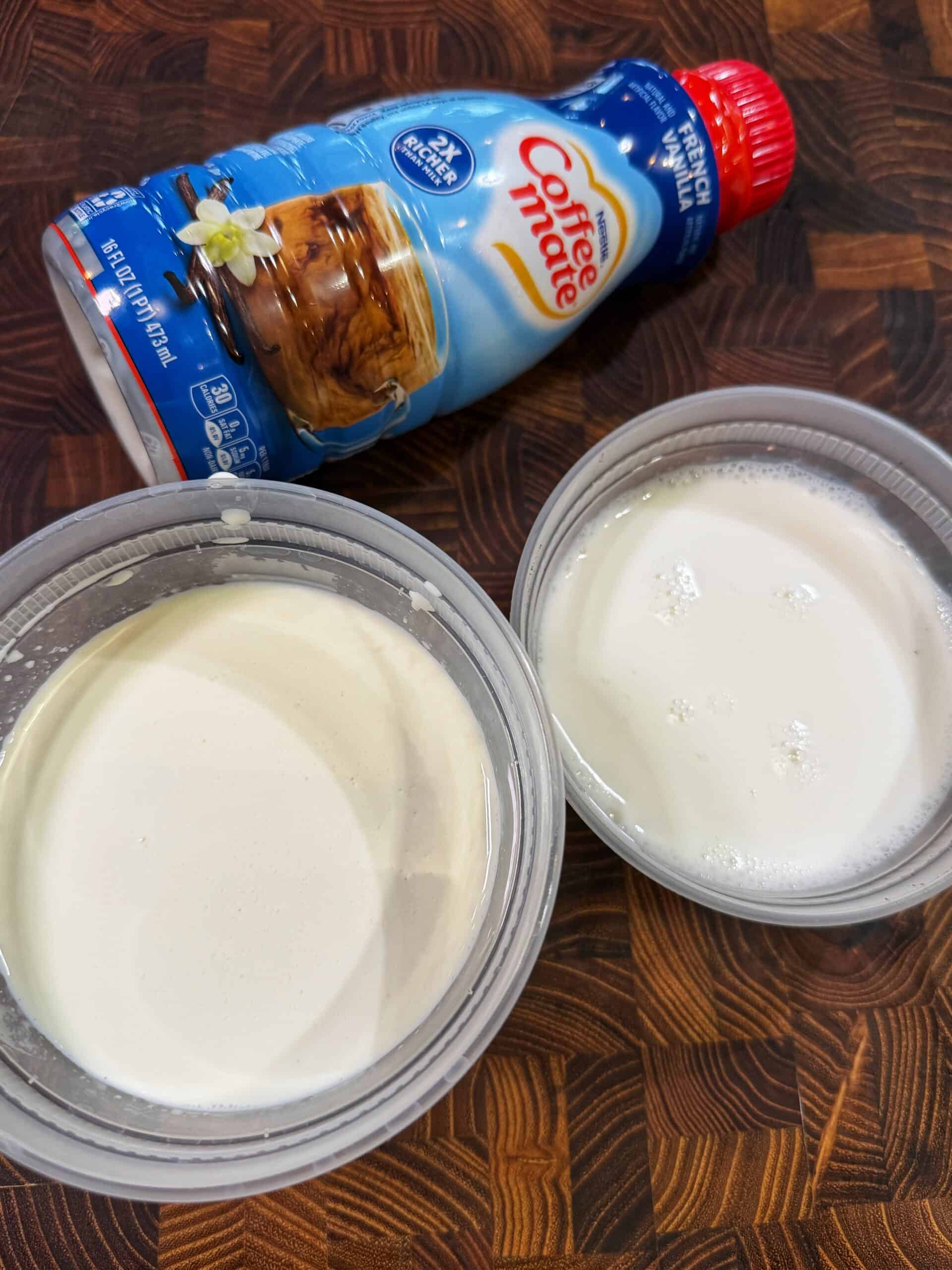 Two plastic containers filled with a creamy white liquid sit on a wooden surface next to a bottle of Coffee Mate French Vanilla coffee creamer.