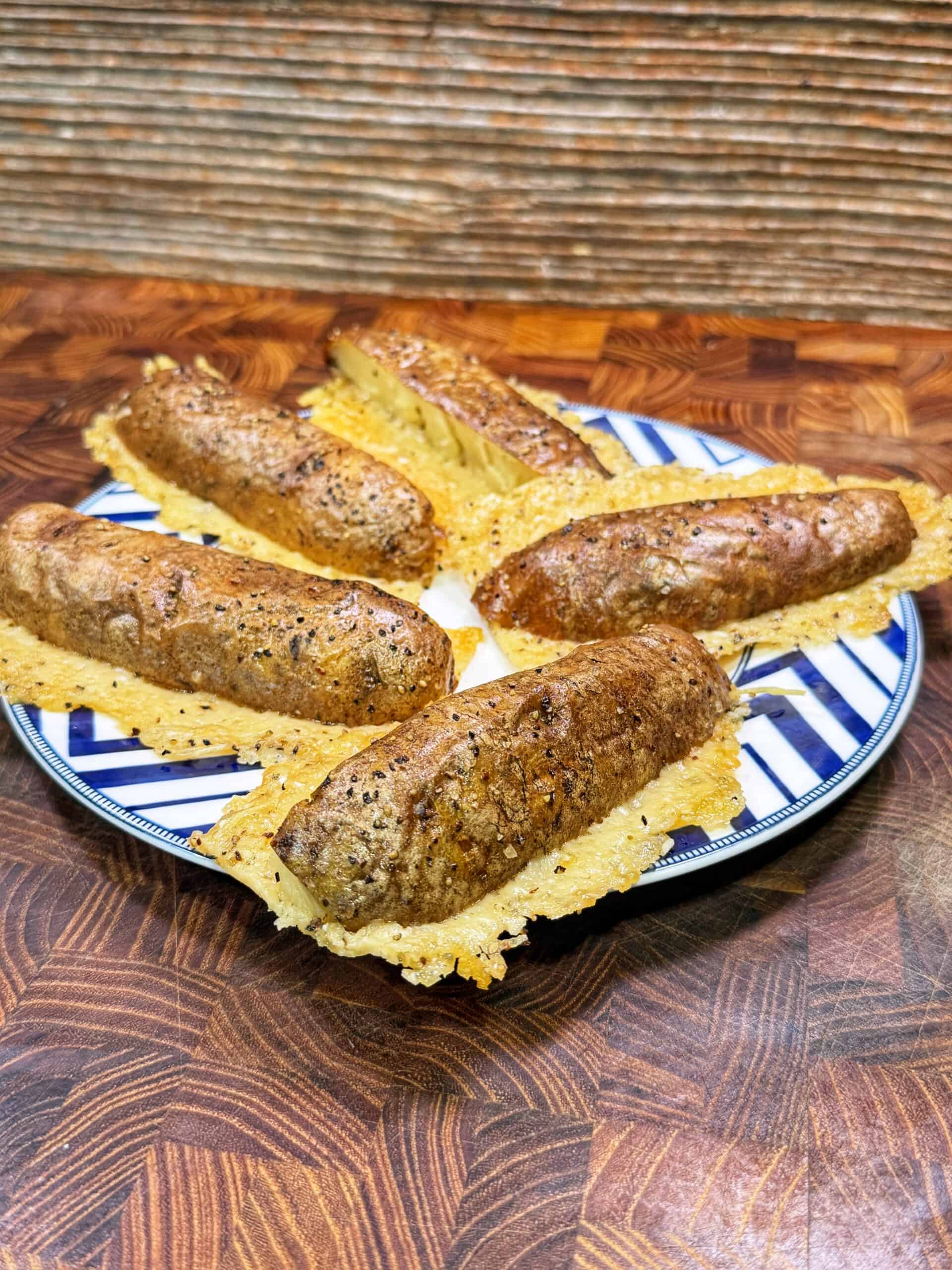 Five parmesan crusted potatoes crispy cheese on a blue and white striped plate, sitting on a patterned wooden surface with a textured wooden background.