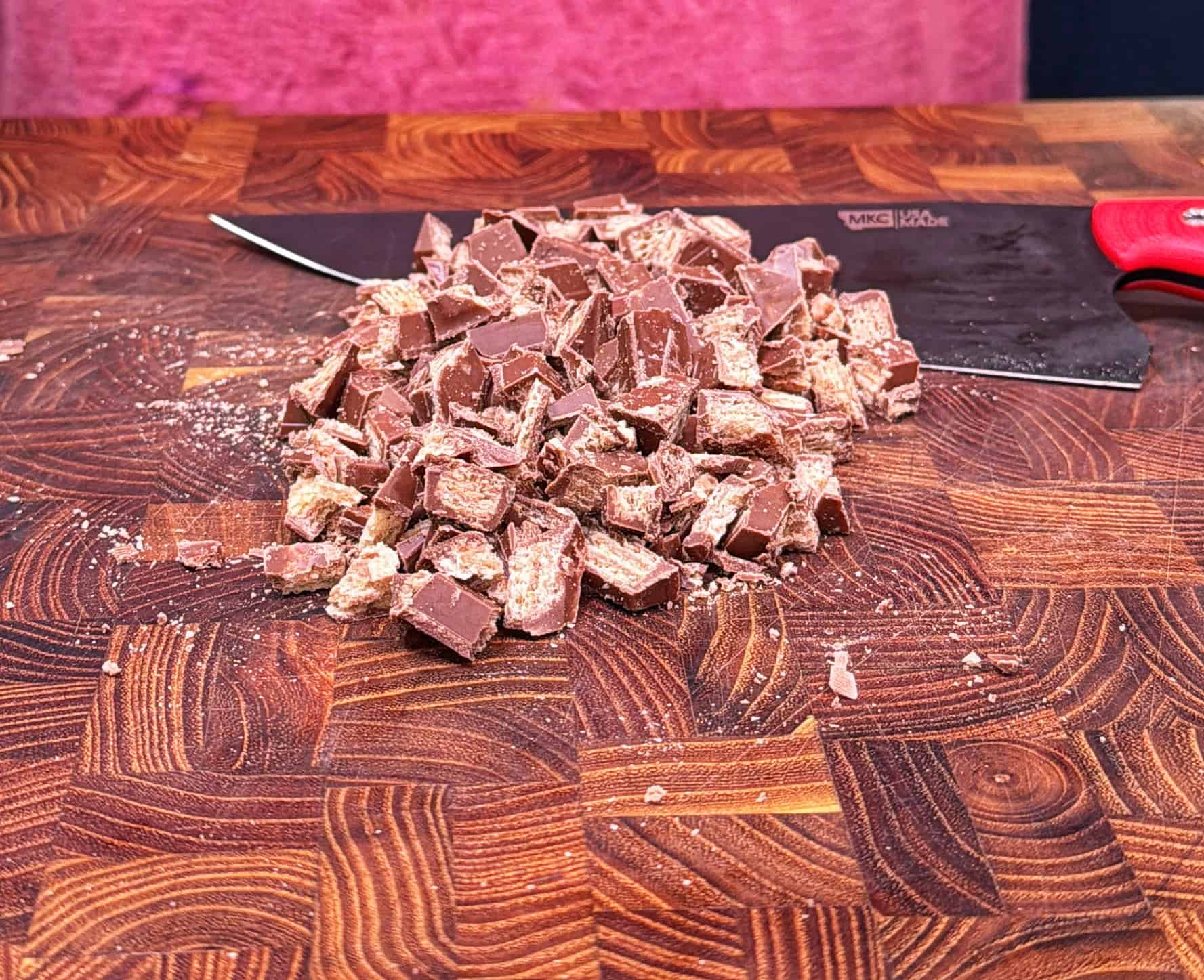 Chopped pieces of chocolate-covered candy bars piled on a wooden <a href=