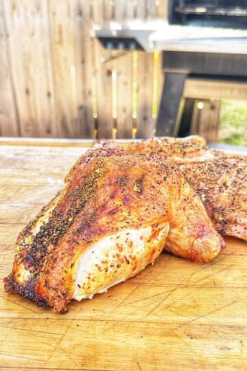 Seasoned frog-cut chicken resting on a wooden cutting board.