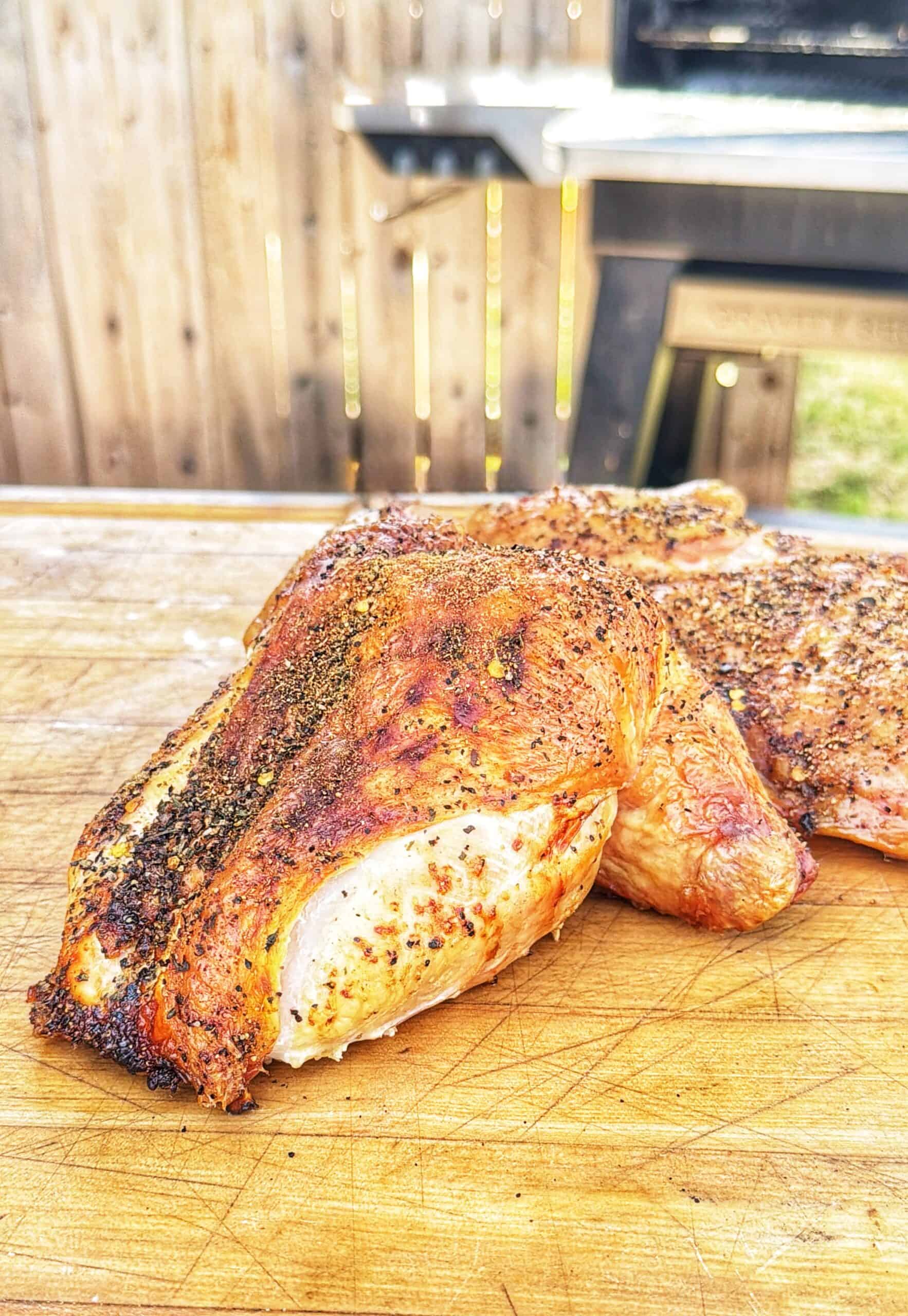 Seasoned frog-cut chicken resting on a wooden cutting board.