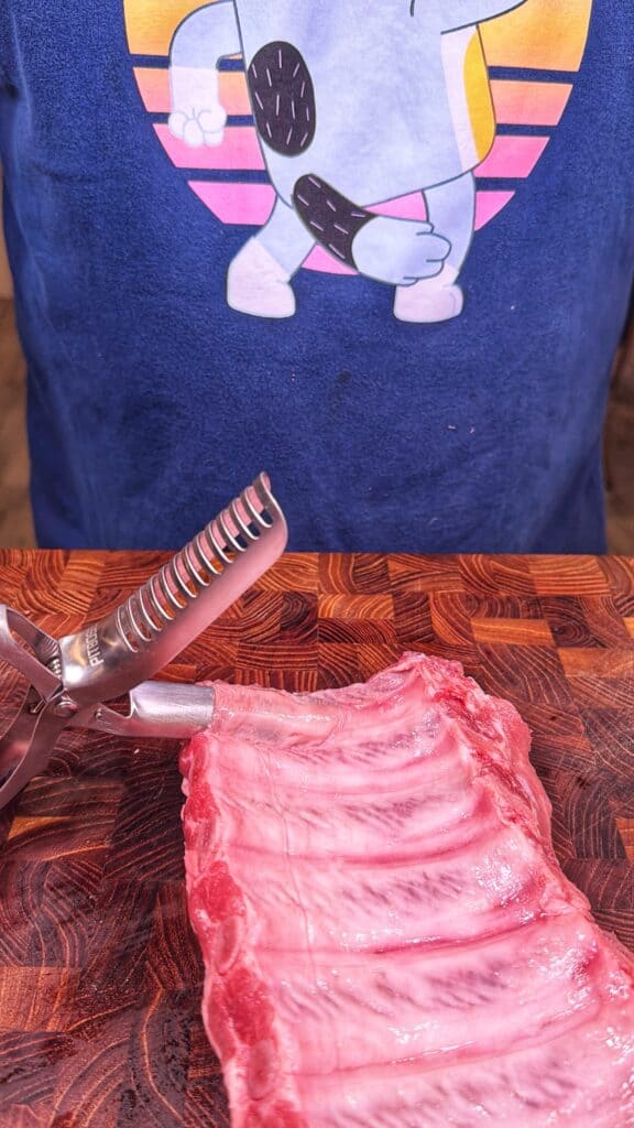 Raw pork ribs on a wooden cutting board with kitchen shears.
