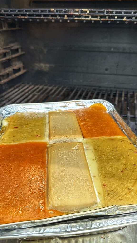 Queso ingredients melting in a foil tray inside a smoker