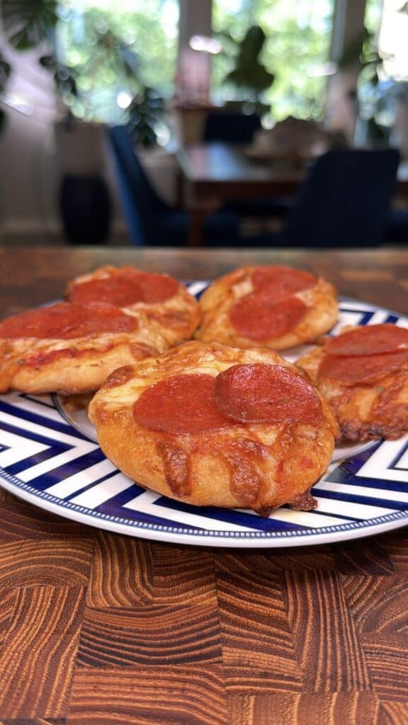 Four mini pepperoni pizzas on a plate.