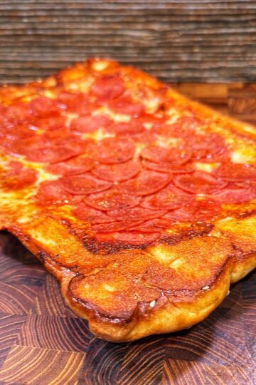 Rectangular upside-down sheet pan pizza with a golden crust and pepperoni slices.