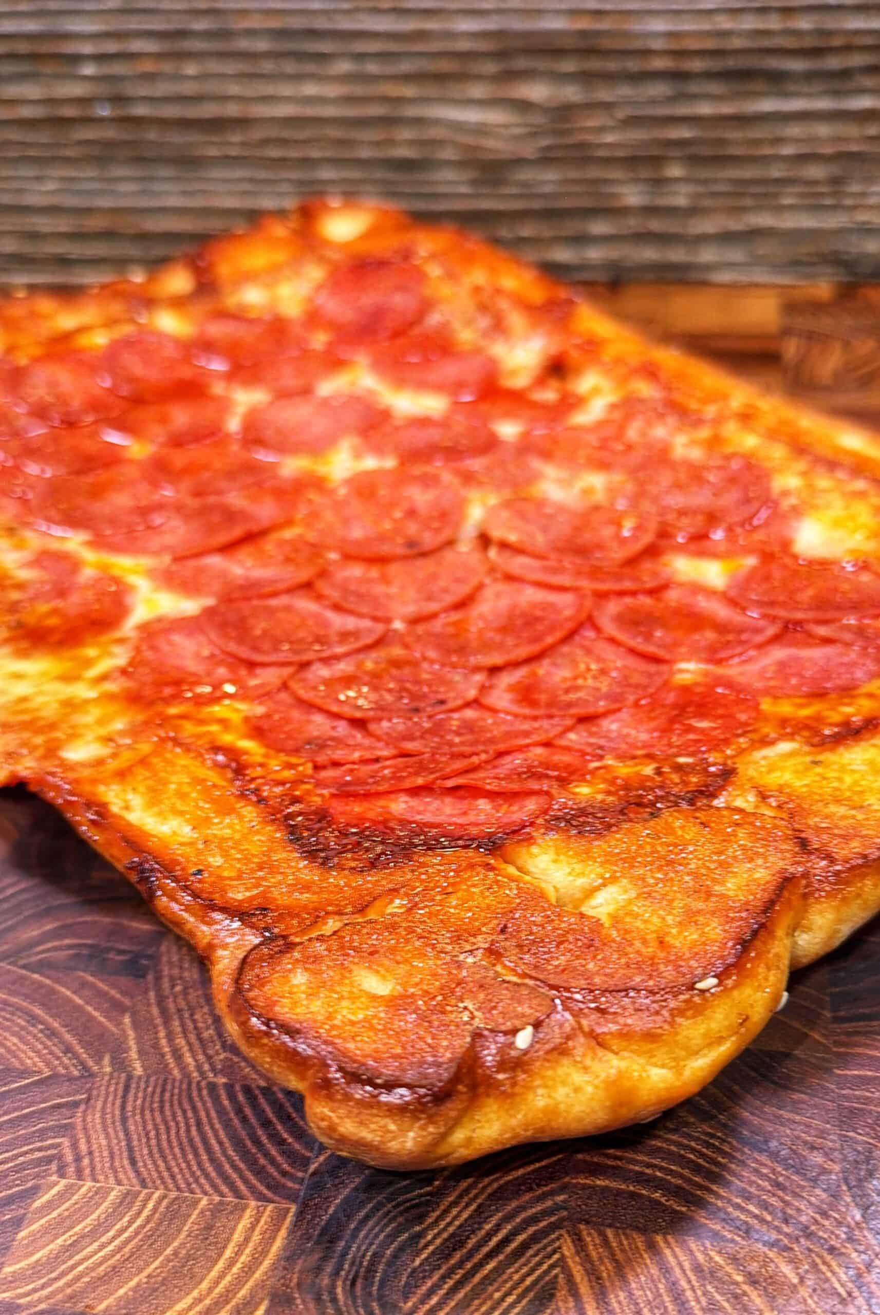 Rectangular upside-down sheet pan pizza with a golden crust and pepperoni slices.