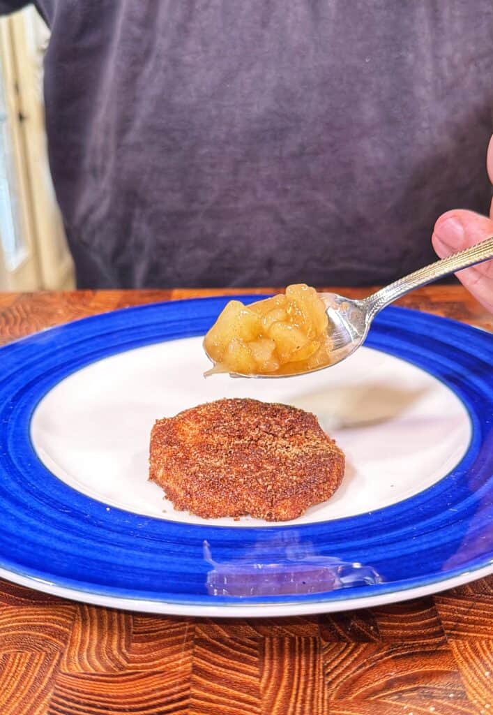 A spoonful of apple pie filling held above a cinnamon sugar coated biscuit half on a plate