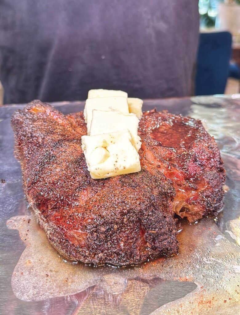 A seasoned cooked chuck roast with cubes of beef tallow melting on top.