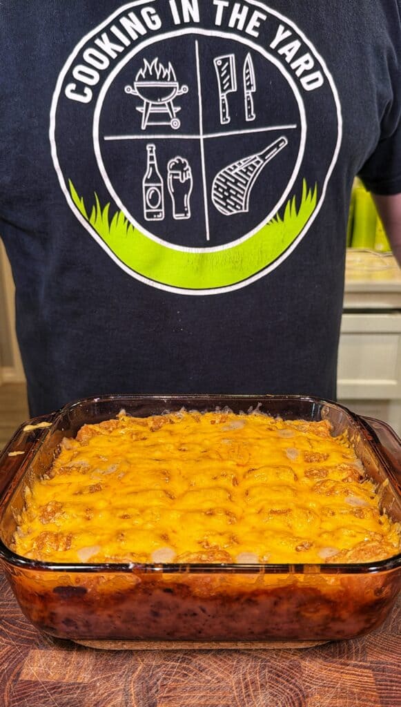 A glass baking dish of cheeseburger tater tot casserole topped with melted shredded cheese.
