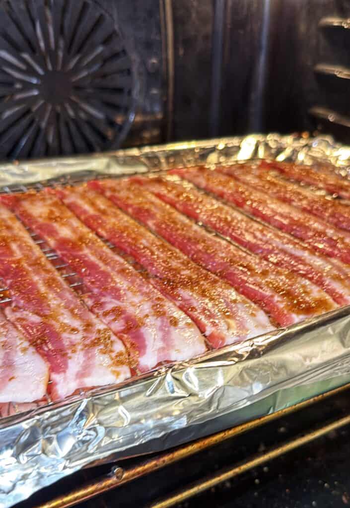 Raw bacon strips arranged on a foil-lined baking sheet, ready for baking.