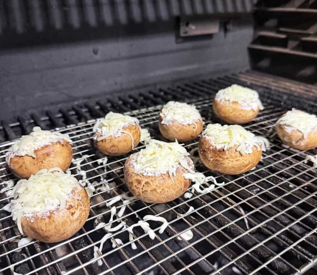 Mushroom caps topped with cheese arranged on a wire rack.