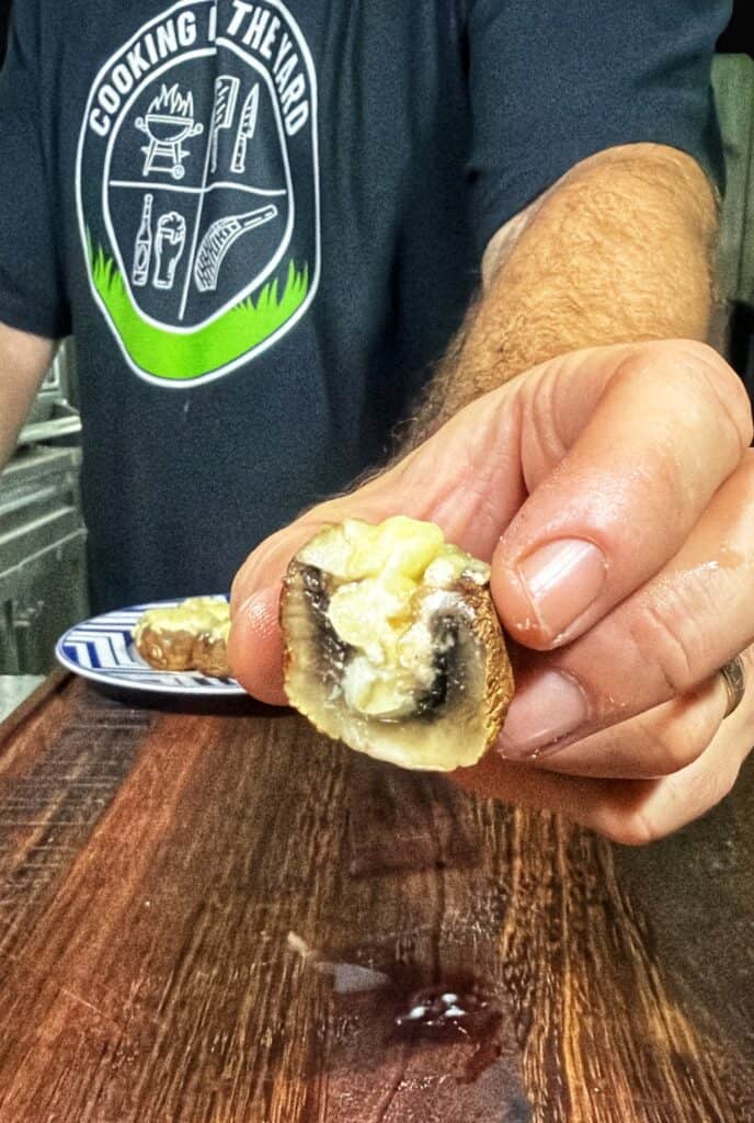 Stuffed mushroom cap filled with melted cheese, with more mushrooms in the background.