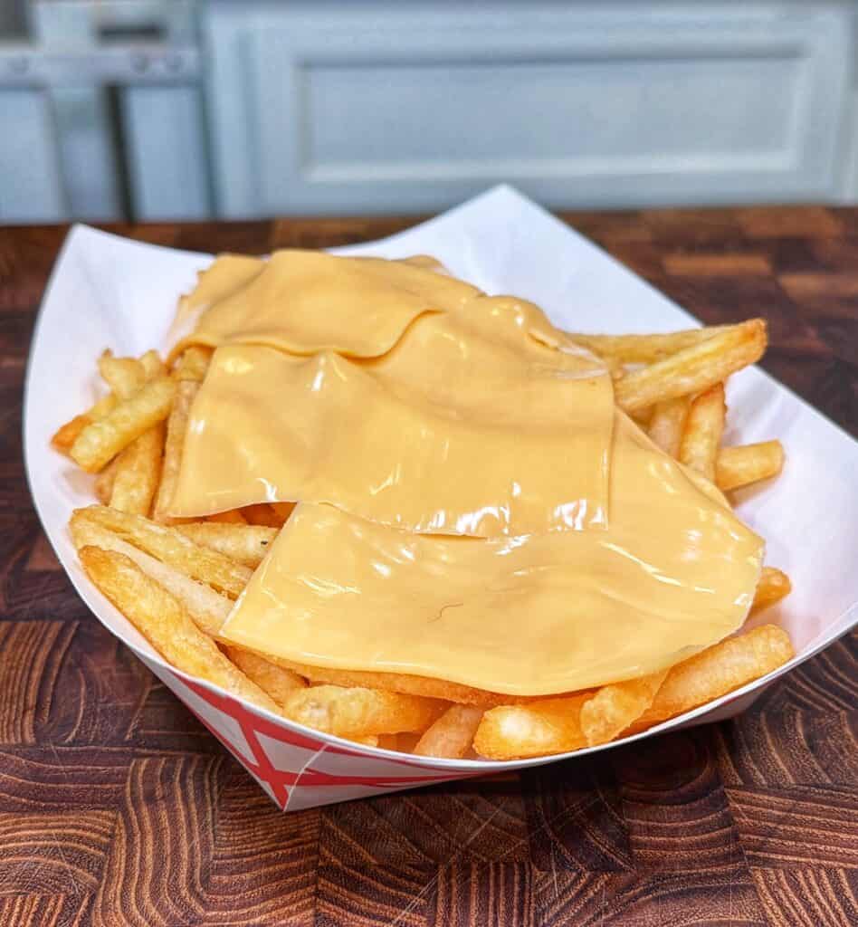A paper basket filled with Cajun steak fries topped with melted cheese.