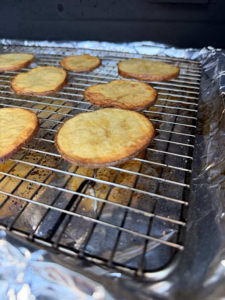 Golden-brown potato slices roasting on a wire rack over a foil-lined baking sheet.